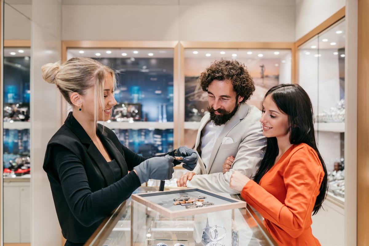 Jewelry associate helping a couple choose a piece in store