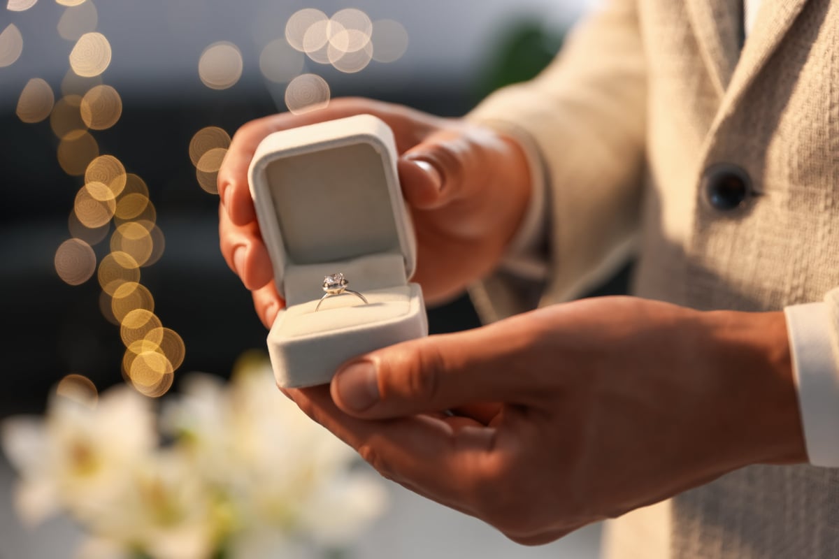Offering an engagement ring during a proposal, softly backlit