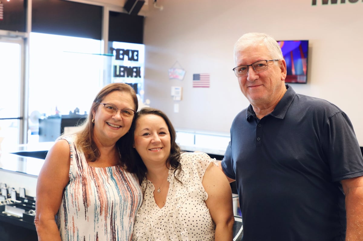 Three team members smiling at the counter inside Cartersville Jewelry Exchange